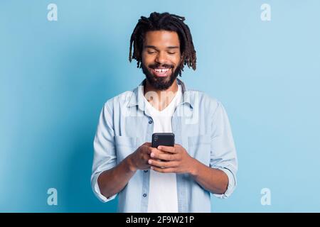 Ritratto di attraente ragazzo focalizzato allegro utilizzando il dispositivo chatting gratuito tempo isolato su sfondo di colore blu brillante Foto Stock