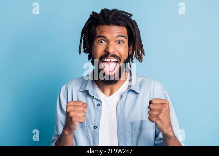 Ritratto di attraente allegro ragazzo stupito festeggiando grandi notizie fresche vittoria di successo isolata su sfondo di colore blu brillante Foto Stock