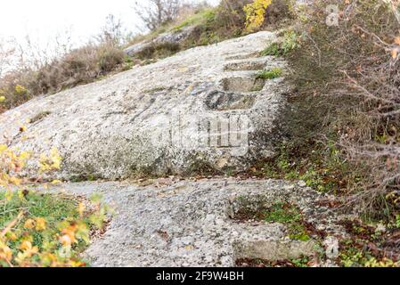 I gradini sono stati tagliati nella roccia. Il sole splende sui gradini della roccia. Dicembre nella Crimea vicino a Sevastopol. Foto Stock