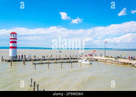 PODERSDORF, AUSTRIA, 9 LUGLIO 2016: I giovani sono kite surf vicino famoso faro rosso e bianco a Podersdorf am See in Austria.Town. Foto Stock