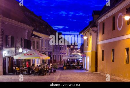 SIBIU, ROMANIA, 6 LUGLIO 2015: La gente sta cenando in un ristorante con una vista spettacolare della cattedrale luterana di santa maria nel sib rumeno Foto Stock