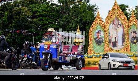 Bangkok, Thailandia. 19 Apr 2021. Un tuk tuk guida attraverso i ritratti della famiglia reale tailandese nel quartiere di Dusit. Il taxi Tuk Tuk Tuk è famoso in tutto il mondo. Il taxi a tre ruote è un modo popolare di trasporto locale non-metered per la gente del posto e i turisti, la tariffa è negoziata in base alla distanza. Il risciò motorizzato tailandese, è un simbolo della nazione. Credit: SOPA Images Limited/Alamy Live News Foto Stock