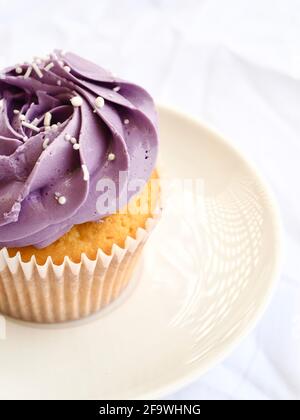 Cupcake viola da vicino su uno sfondo bianco testurizzato Foto Stock