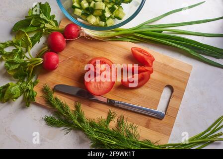 pomodoro affettato su un tagliere e verdure Foto Stock