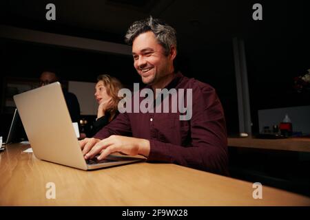 Ritratto di un uomo d'affari riuscito di mezza età che scrive sul laptop sul posto di lavoro Foto Stock