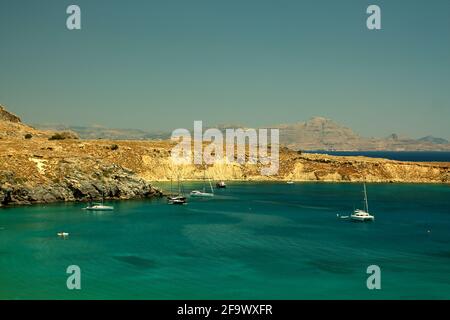 Bella vista di una collina vicino a belle acque blu con le barche su di esso a Rodi, Grecia Foto Stock