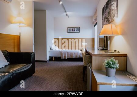 Interno di una camera d'hotel semplice e ben arredata camera da letto separata durante il giorno Foto Stock