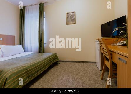 Interno di una camera d'hotel semplice e ben arredata camera con letto matrimoniale durante il giorno Foto Stock