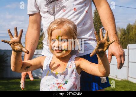 Primo piano ritratto di bambina bella. La ragazza è macchiata di acquerelli, divertenti attività di svago in giardino. Foto Stock