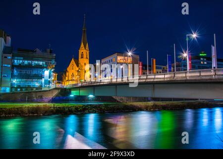 VILLACH, AUSTRIA, 20 FEBBRAIO 2016: Vista notturna di un ponte sul fiume drau con la torre della chiesa di san nikolai a villach, austria. Foto Stock