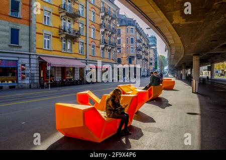 ZURIGO, SVIZZERA, 24 OTTOBRE 2015: La gente siede sulle panchine di design moderno sotto l'autostrada nel centro di Zurigo Foto Stock