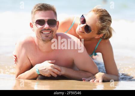 Giovane uomo e donna in occhiali da sole sdraiati in riva al mare Foto Stock