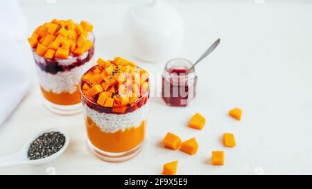 primo piano di due bicchieri con purea di zucca chia pudding e. marmellata di fragole su piatto bianco Foto Stock