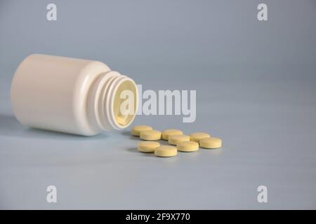 Pillole in vaso di plastica aperto capovolto. Concetto di medicina di farmaci, compresse, medicinali e pillole su sfondo grigio. Spazio di copia. Messa a fuoco selettiva. Foto Stock