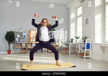 Lavoratore di ufficio in forma divertente che ha allenamento fitness con manubri durante giorno lavorativo Foto Stock