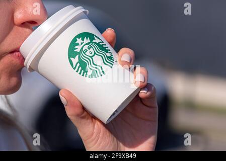 BERLINO - Apr 17: Una donna che tiene una tazza di carta con il logotipo Starbucks in una strada di Berlino, aprile 17. 2021 in Germania Foto Stock