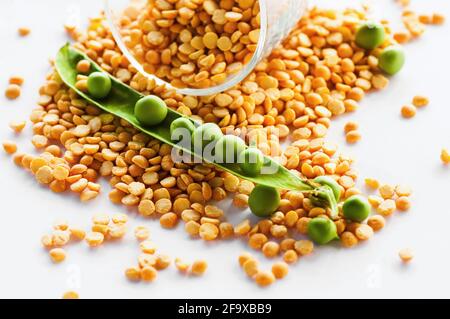 Piselli verdi secchi e freschi in legume aperto su fondo bianco con vetro, guardaroba. Foto Stock