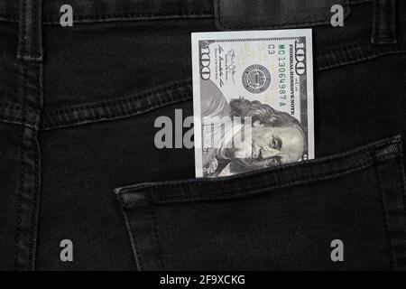 Un conto di cento dollari che si stacca dalla tasca di jeans neri