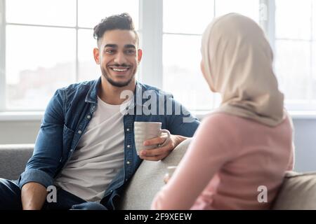 Felice uomo medio-orientale che condivide idee con la sua fidanzata Foto Stock