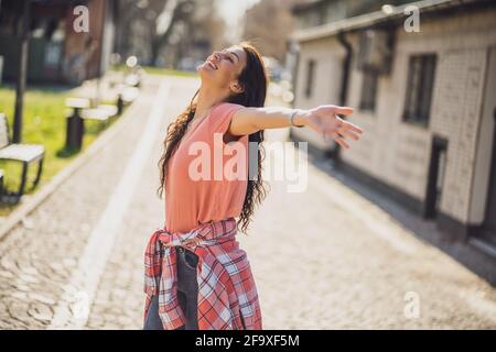 Felice giovane donna sta godendo di una giornata di sole all'aperto in città. Foto Stock
