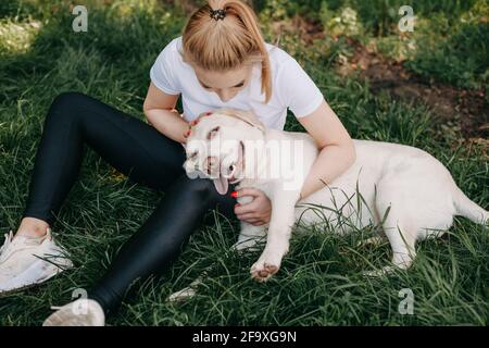Foto in alto di una donna caucasica che abbraccia il suo oro retriever sdraiato sull'erba Foto Stock