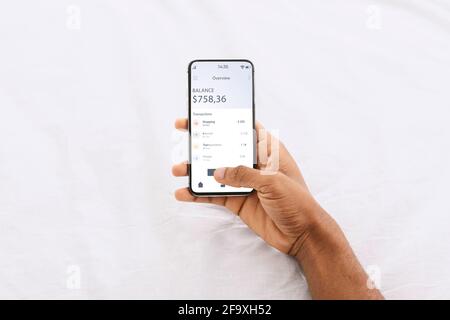 Uomo afro-americano che utilizza l'app finanziaria sullo smartphone Foto Stock