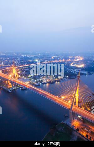 Vista aerea dei ponti sospesi e delle autostrade che si snodano sul fiume Chao Phraya al crepuscolo. Le luci luminose attraversano i ponti. Thailandia. Foto Stock