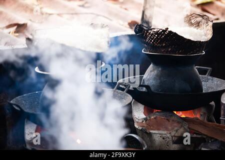 Cucina di riso appiccicoso sul tradizionale vaporizzatore a cono di bambù su legna, cena di cucina in una tipica casa del Laos, Luang Prabang, Sito Patrimonio dell'Umanità. Foto Stock