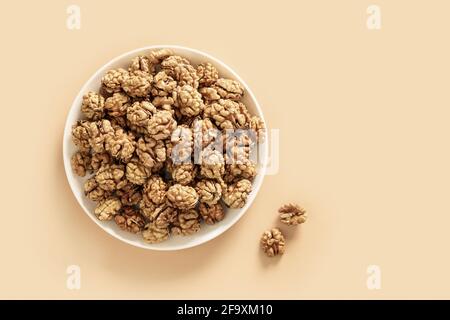 Noci sane senza conchiglie in piastra bianca su sfondo beige con spazio copia. Vista dall'alto. Foto Stock