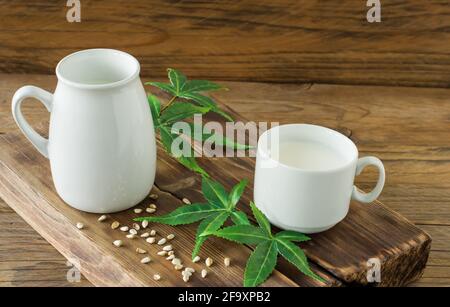 Cannabis glutine vegano a base di erbe e latte senza lattosio e foglie di cannabis su tavola di legno. Foto Stock