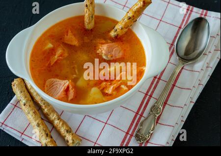 zuppa fatta in casa con salmone con bastoncini di pane su fondo di cemento. Foto Stock