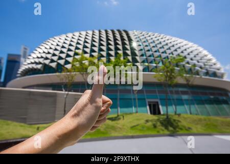 Grande pollice in alto durante la visita al design della struttura a cupola dell'Esplanade sul tetto, Singapore. Foto Stock