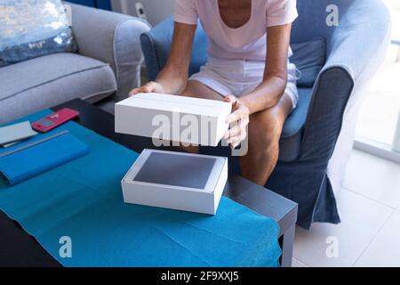 Donna anziana che sboxe un nuovo mini tablet Apple ipad nel suo soggiorno. Foto Stock