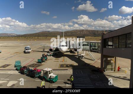 rifornimento in aereo, spedizione di bagagli e carico di passeggeri dopo un volo e in prossimità di ripartire di nuovo dall'aeroporto con le montagne Foto Stock