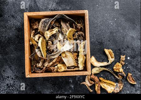 Boletus funghi secchi selvatici in una scatola di legno. Sfondo nero. Vista dall'alto Foto Stock