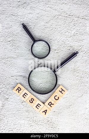 Lente d'ingrandimento nera con testo di ricerca su sfondo grigio chiaro. Analisi statistica e ricerca scientifica. Foto Stock