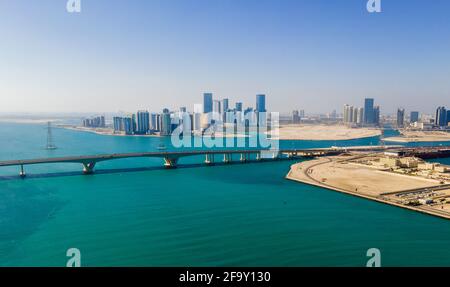 Vista aerea dello skyline di Abu Dhabi che si erge sul mare Formare il moderno lungomare della capitale degli Emirati Arabi Uniti all'alba Foto Stock