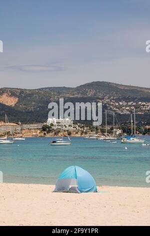 Palmanova, Maiorca, Spagna. 20 Apr 2021. Vista sulla spiaggia di una donna e una tenda a vento di fronte al mare e barche a Pamanova a Maiorca. Credit: John-Patrick Morarescu/ZUMA Wire/Alamy Live News Foto Stock