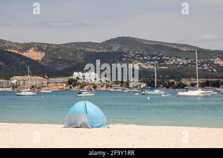 Palmanova, Maiorca, Spagna. 20 Apr 2021. Vista sulla spiaggia di una donna e una tenda a vento di fronte al mare e barche a Pamanova a Maiorca. Credit: John-Patrick Morarescu/ZUMA Wire/Alamy Live News Foto Stock