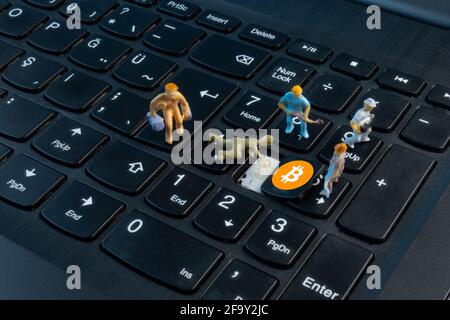 Mini lavoratori che lavorano su Bitcoin sulla tastiera Foto Stock