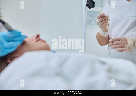 Immagine focalizzata delle braccia del medico durante la procedura medica in bellezza clinica Foto Stock