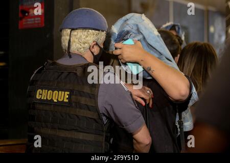 San Paolo, San Paolo, Brasile. 21 Apr 2021. Una donna viene ricercata da un ufficiale di polizia femminile mentre lascia un partito clandestino a Sao Paulo nelle prime ore di mercoledì 21. Circa 120 persone erano sul posto, la maggior parte senza uno scudo facciale, bere e fumare hookah, trascurando le condizioni di salute e non rispettando la quarantena contro Covid-19. In una stanza nascosta, ci erano 9 slot machines illegali. Il proprietario del bar è stato arrestato e pagherà circa 400 mila reais in multe per la violazione della legge. Credit: Paulo Lopes/ZUMA Wire/Alamy Live News Foto Stock