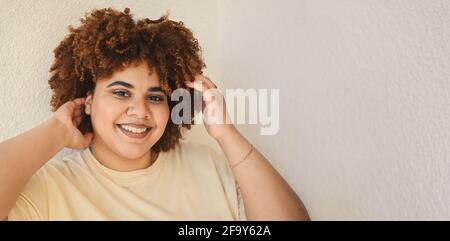 Bella felice sorridente curvy Plus taglia African nero donna afro capelli con make up in posa beige t-shirt su sfondo bianco. Imperfezione del corpo, accettazione del corpo, corpo positivo e concetto di diversità. Foto Stock