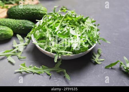 Foglie di arugula fresche in ciotola su tavola scura. Cibo vegetariano fresco concetto Foto Stock