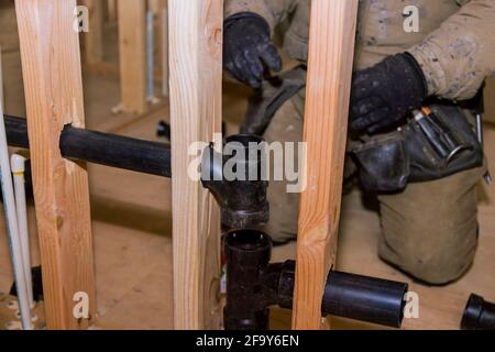 Operatore che utilizza colla con raccordo per installare il tubo di scarico in PVC nell'area di lavoro. Foto Stock