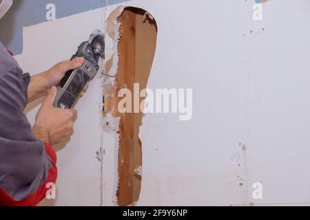 Casa danni interni per cartongesso con riparazione casa di uomo che taglia  cartongesso utilizzando utensili elettrici ad angolo Foto stock - Alamy