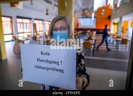 21 aprile 2021, Meclemburgo-Pomerania occidentale, Lübz: Il coordinatore della scuola superiore Maren Wende appone un cartello sugli esami Abitur su una porta di vetro di fronte alla sala esame di Eldenburg-Gymnasium. Il 23.04.2021, la fase di esame di Abitur a Meclemburgo-Vorpommern inizia con gli esami scritti in inglese. L'inizio degli esami di Abitur era stato rinviato di dieci giorni a causa di Corona. Foto: Jens Büttner/dpa-Zentralbild/dpa Foto Stock