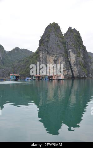 Vista panoramica delle acque verdi, delle formazioni rocciose e delle case galleggianti e delle barche sulla Baia di ha Long in Vietnam Foto Stock