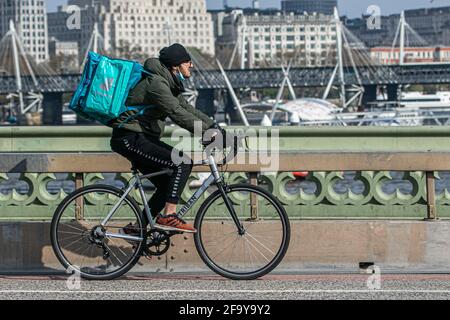 WESTMINSTER LONDON, REGNO UNITO. 21 aprile 2021. Un pilota Deliveroo con uno zaino in sella al Westminster Bridge. Il fondatore di Deliveroo Will Shu ha riferito che i volumi d'ordine sono più che raddoppiati a 71m nel primo trimestre del 2021, con anche il numero di clienti in forte aumento durante il terzo blocco, anche se le azioni di deliveroo sono diminuite dopo che l'azienda ha iniziato a commerciare due settimane fa. Credit amer Ghazzal/Alamy Live News Foto Stock