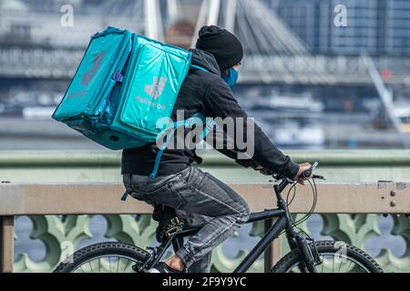 WESTMINSTER LONDON, REGNO UNITO. 21 aprile 2021. Un pilota Deliveroo con uno zaino in sella al Westminster Bridge. Il fondatore di Deliveroo Will Shu ha riferito che i volumi d'ordine sono più che raddoppiati a 71m nel primo trimestre del 2021, con anche il numero di clienti in forte aumento durante il terzo blocco, anche se le azioni di deliveroo sono diminuite dopo che l'azienda ha iniziato a commerciare due settimane fa. Credit amer Ghazzal/Alamy Live News Foto Stock